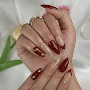 burgundy gold nail designs medium almond press-on nails with burgundy red nude accents french tips and gold star details for winter wedding style