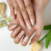 flower summer nails medium almond press-on nails with nude base, zebra french tips, and white 3D flower accents