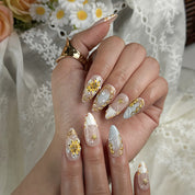 nail designs gold and white medium almond press-on nails with nude base gold details white accents yellow flower and pearl touches summer beach party style