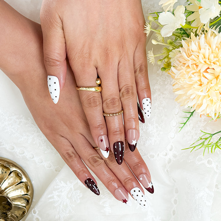 nails white and pink medium almond press-on nails with white and cocoa-red french tips, polka dots, and star accents for fall holiday look