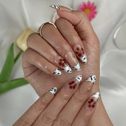 nude french tip nails medium almond press-on nails with nude base white french tips and simple flower accents summer wedding style