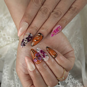 orange nails with designs medium almond press-on nails with pink floral accents and gold metallic highlights for summer and prom