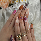 orange nails with designs medium almond press-on nails with pink floral accents and gold metallic highlights for summer and prom