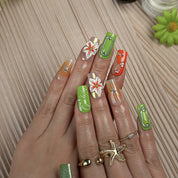 pastel green nails medium square press-on nails with green and orange accents metallic luster and flower details spring beach party style