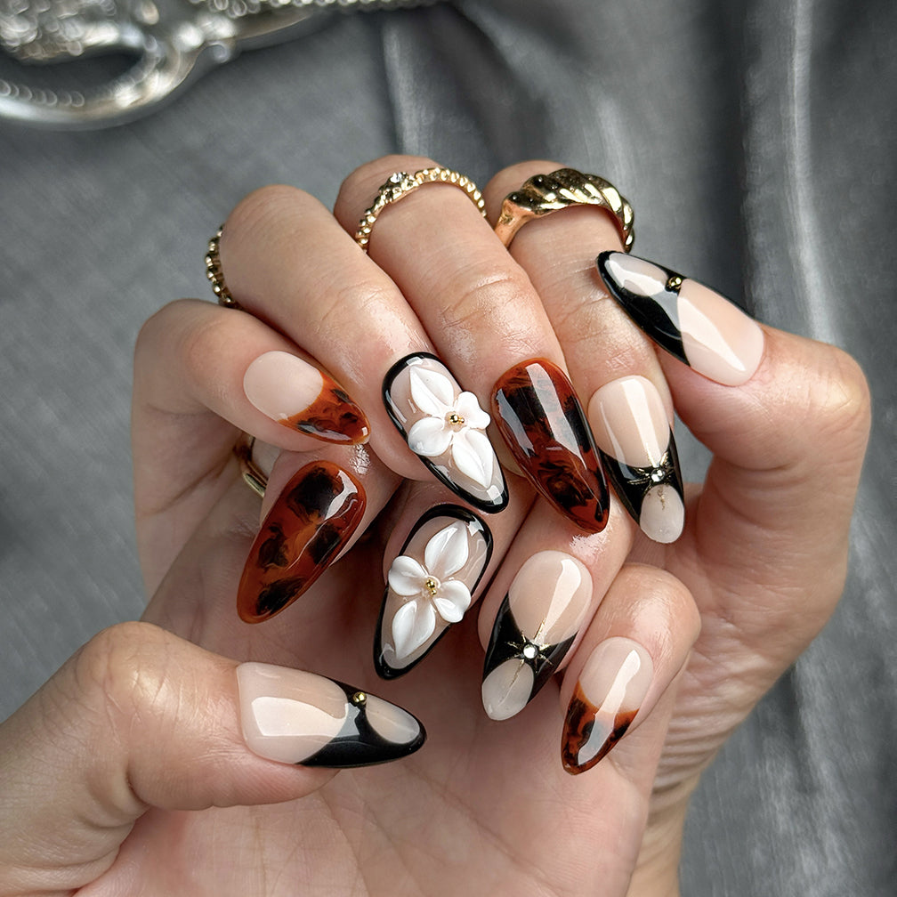 red black nail art medium almond press-on nails with nude base black accents brown marble details and flower accent fall winter holiday style