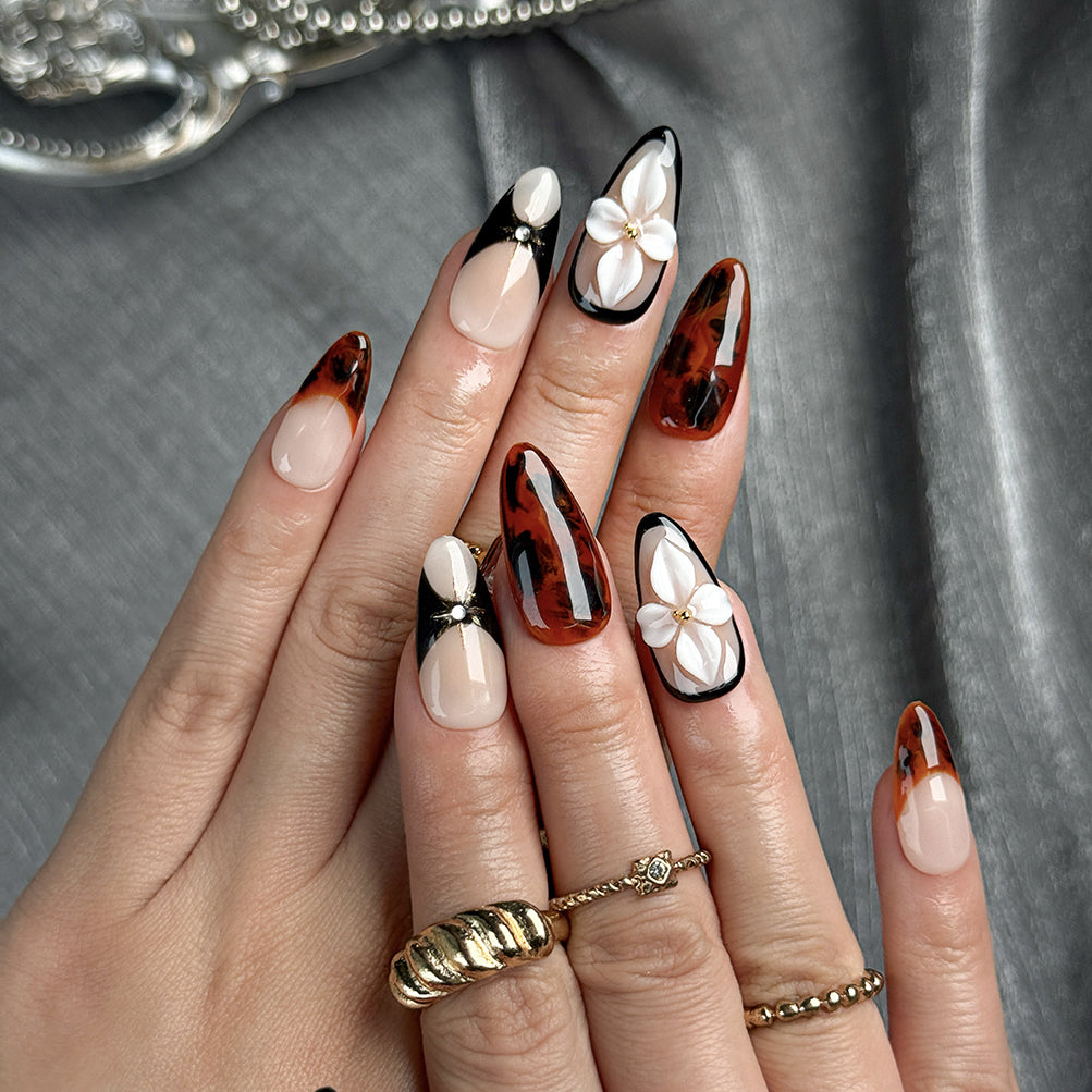 red black nail art medium almond press-on nails with nude base black accents brown marble details and flower accent fall winter holiday style