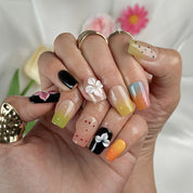 sunset pink and orange ombre nails short square press-on nails with black accents colorful ombre tips and flower details spring beach party style